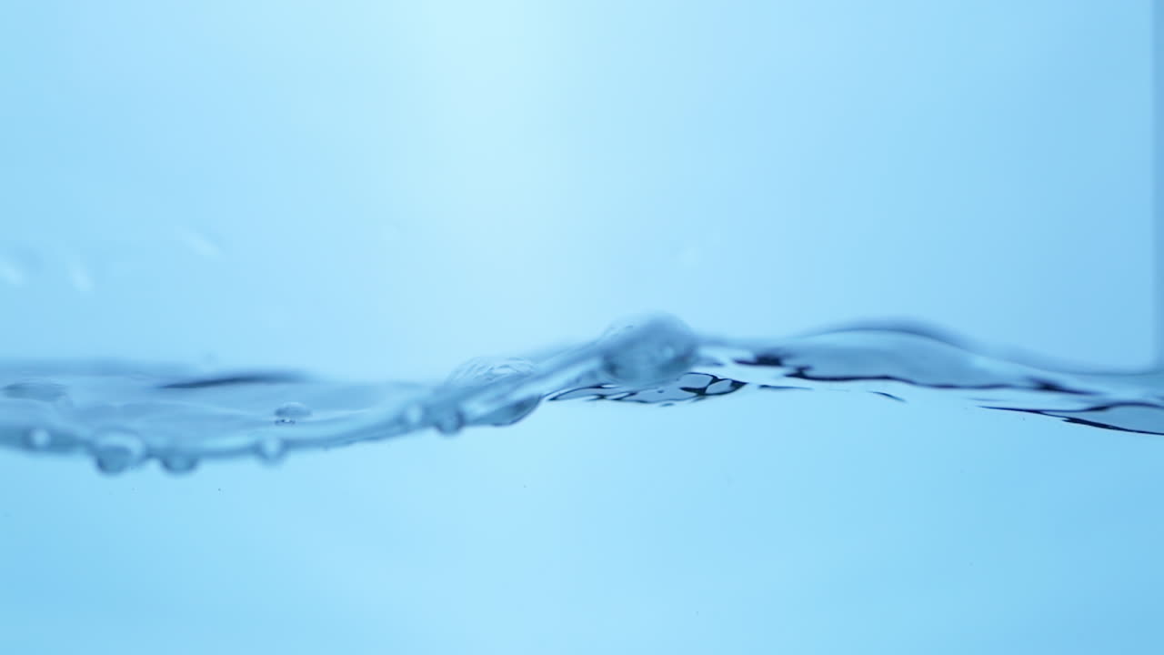 Close-up shot of water droplets suspended in mid-air, showcasing the clarity, freshness, and purity of liquid in a moment of action.