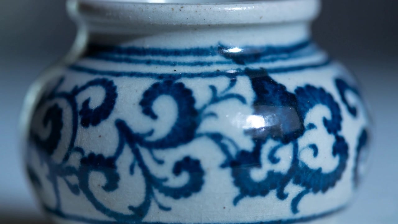 Capturing blue-white jar on tabletop while camera adjusting focus and light, revealing chip detail