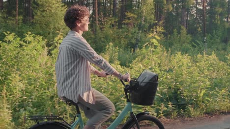 junge glückliche frau mit sonnenbrille und freizeitkleidung, die auf dem waldweg 1 fahrrad fährt