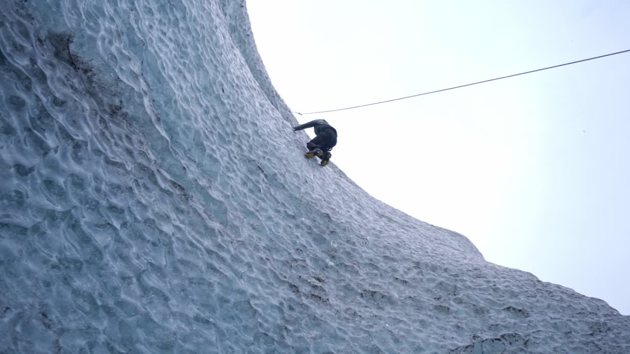 A climber, equipped with an ice axe and rope, scales a majestic, textured blue ice wall of a glacier, showcasing the extreme adventure amidst the vast ice formations of Vatnajökull, Iceland