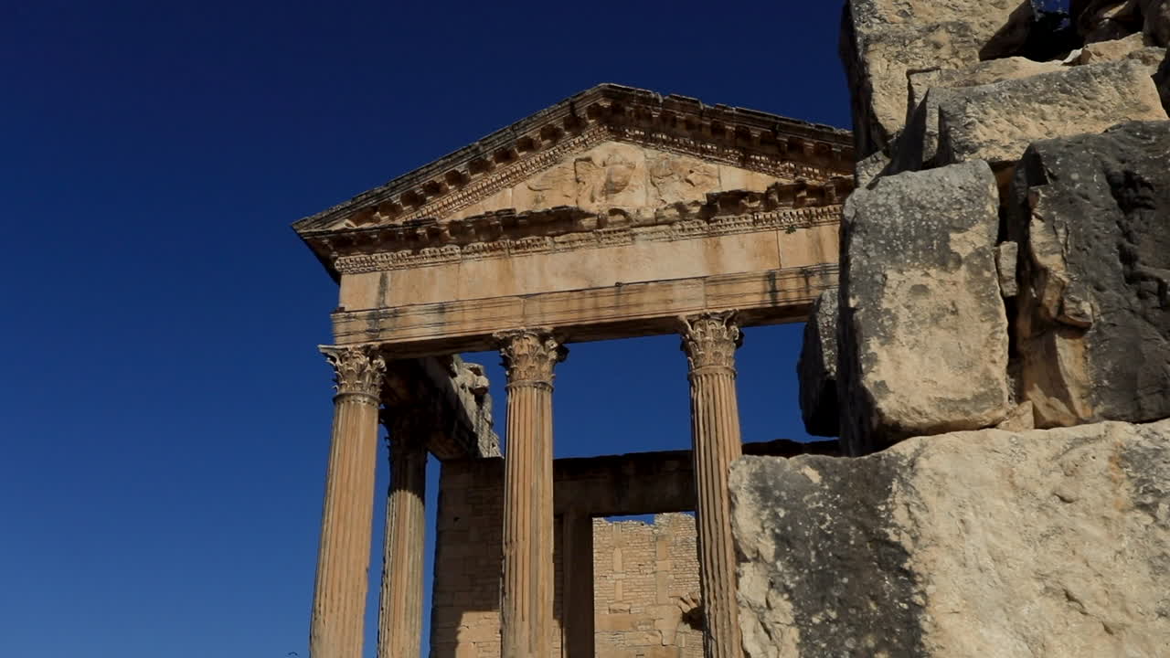 ruinas romanas antiguas iluminadas por el sol en dougga contra un cielo azul claro