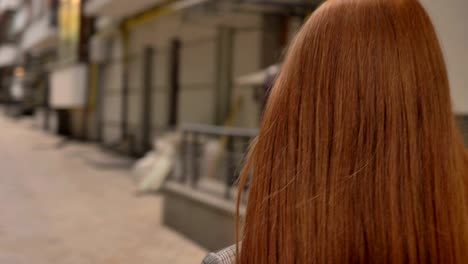 retrato de una joven hermosa mujer pelirroja caminando por la calle de la ciudad y mirando hacia adelante, en círculo