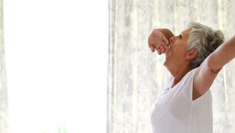 Senior-woman-waking-up-and-stretching-in-bed