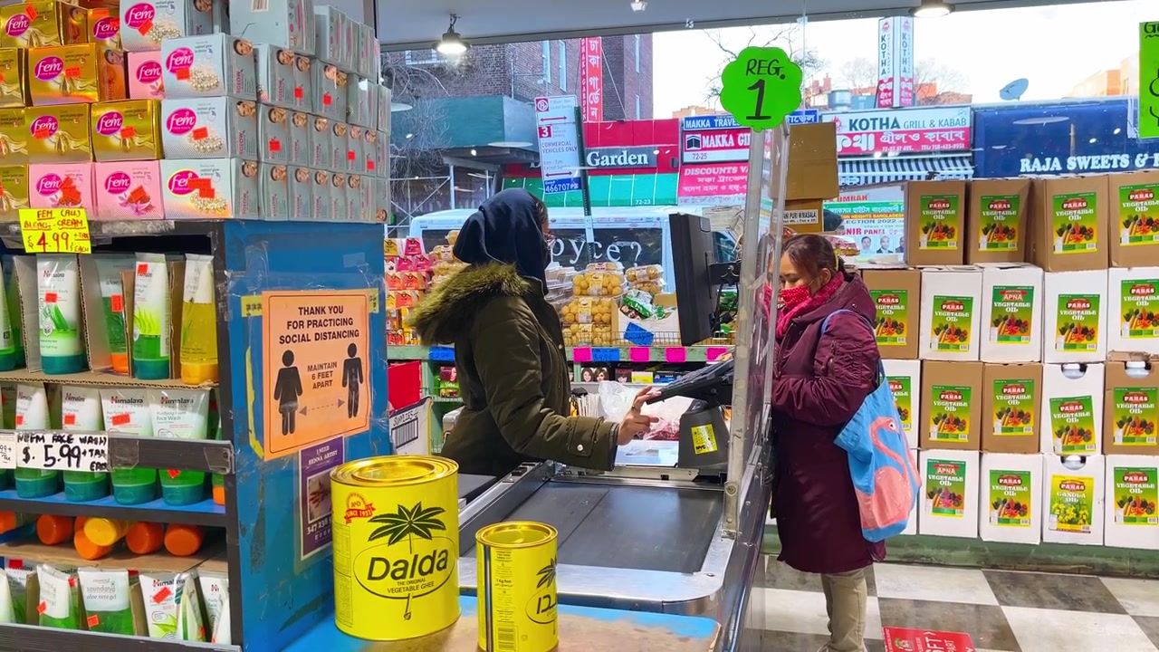 New York, AS, 9 Maret 2022: Kasir memindai belanjaan di konter pembayaran pasar dalam ruangan. Konter pembayaran di dalam toko kelontong dengan kasir, pelanggan, rak produk, tanda jaga jarak, dan pemandangan jalan.