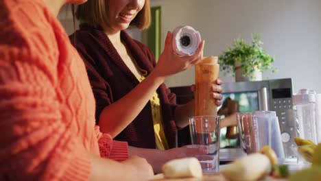 Madre-E-Hija-Asiáticas-Preparando-Una-Bebida-Saludable-En-La-Cocina-Sonriendo