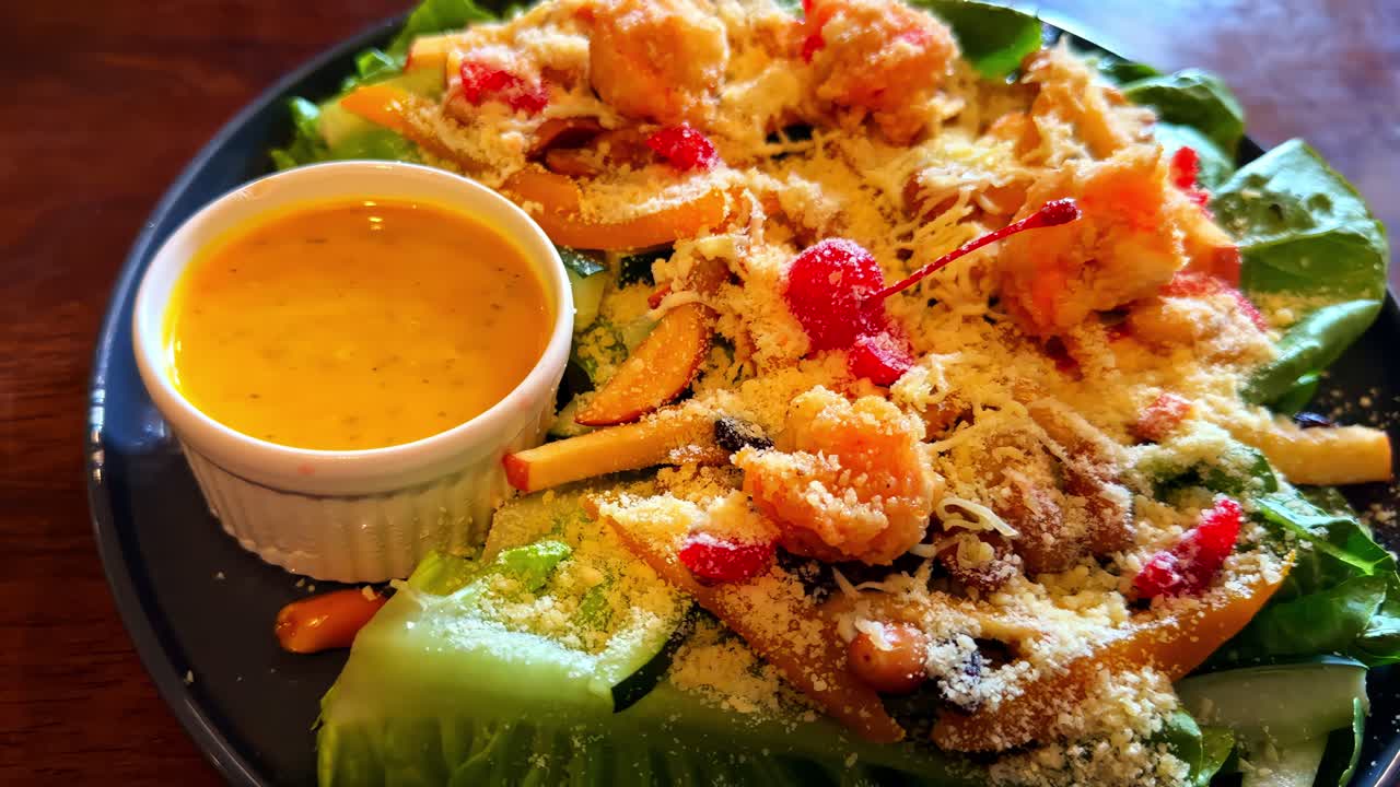 Primo piano di una deliziosa insalata sana con ciotola di condimento su un tavolo di legno