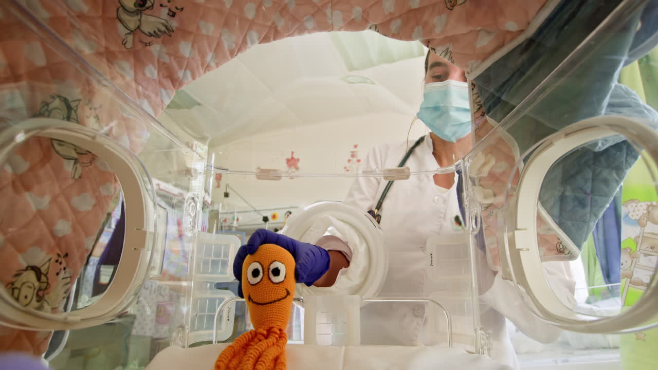 Doctor Examining Baby in Incubator with Toy