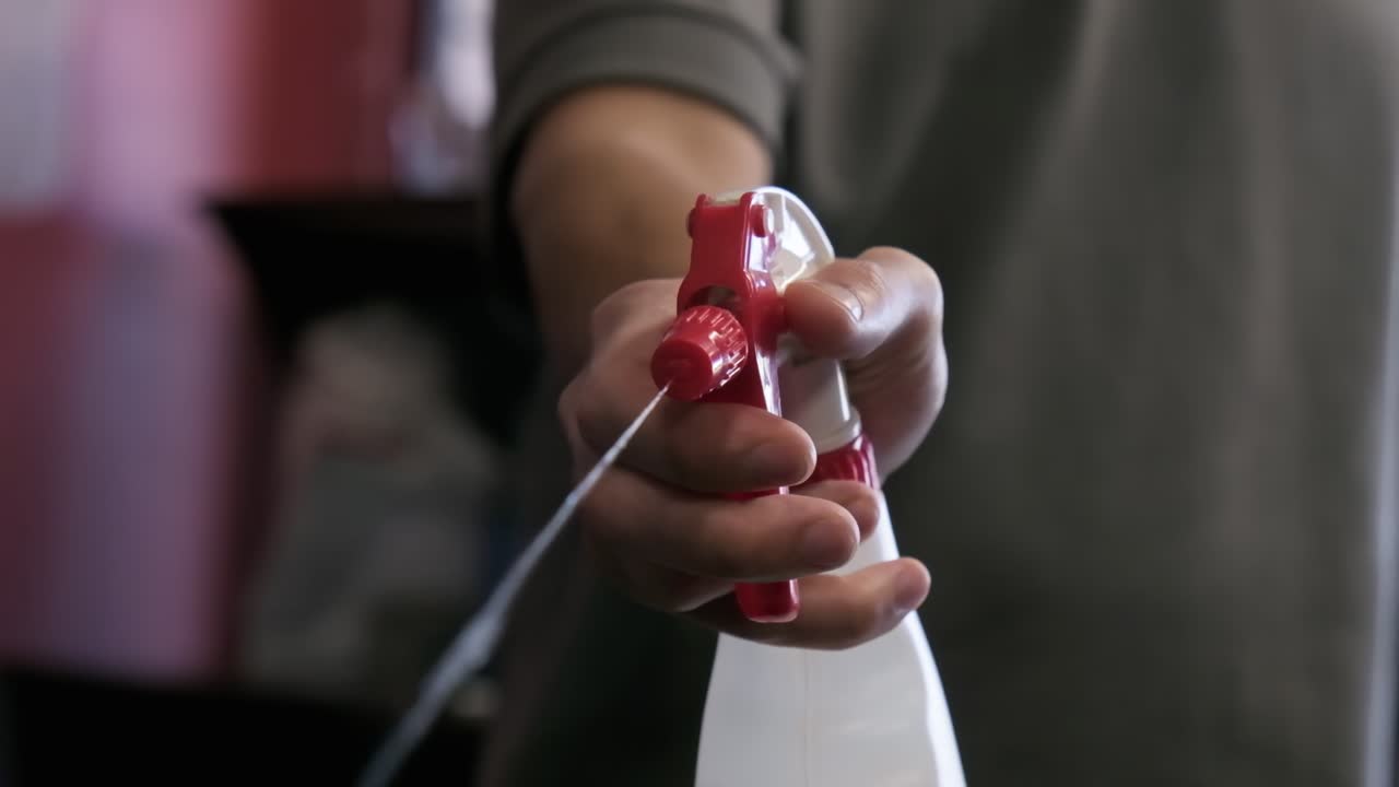 Close up of hand disinfecting tattoo studio by spraying antibacterial bottle. Slow motion.