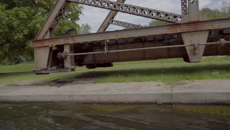 view from a boat cruising down the canal passing a steel swing bridge through the peterborough lock system