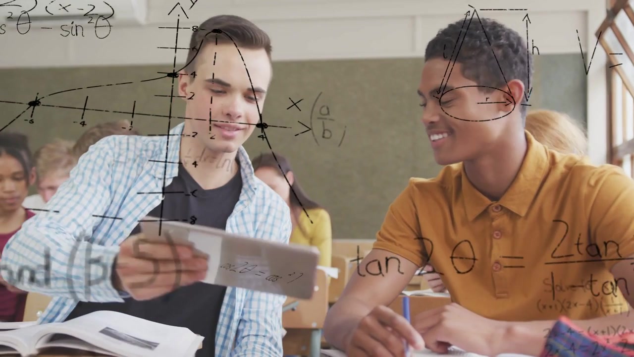 Diverse teenage male students sitting at classroom desk, studying math on tablet and open textbook