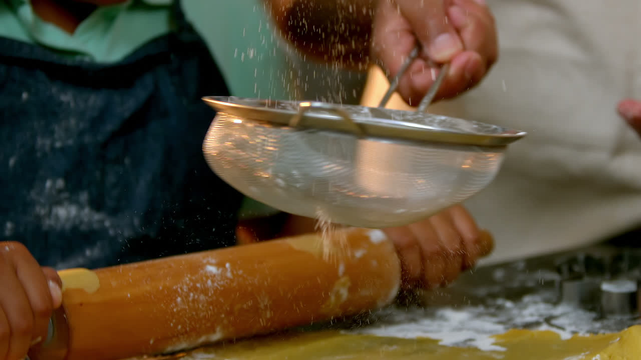 Girl preparing cookie dough with her mother in kitchen