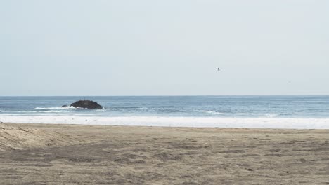 olas del océano pacífico rompiendo en la playa de arena en perú