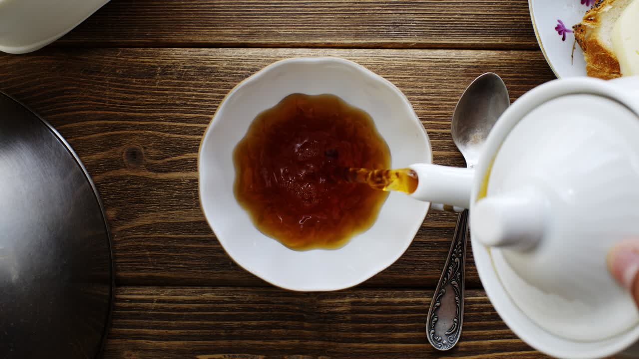 Tea from the kettle slowly pour into porcelain cup