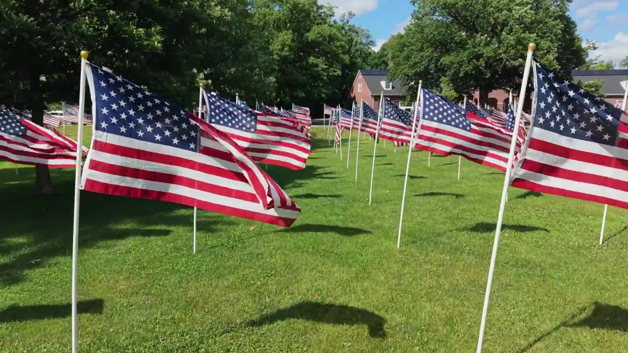 Flying Through American Flags Waving In The Wind During Memorial Day To Honor Personal Heroes. - aerial shot