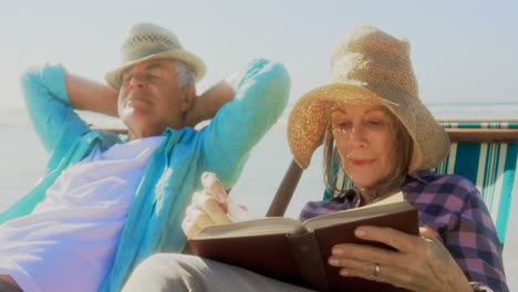 vista frontal de una mujer caucásica mayor activa leyendo un libro en la playa 4k