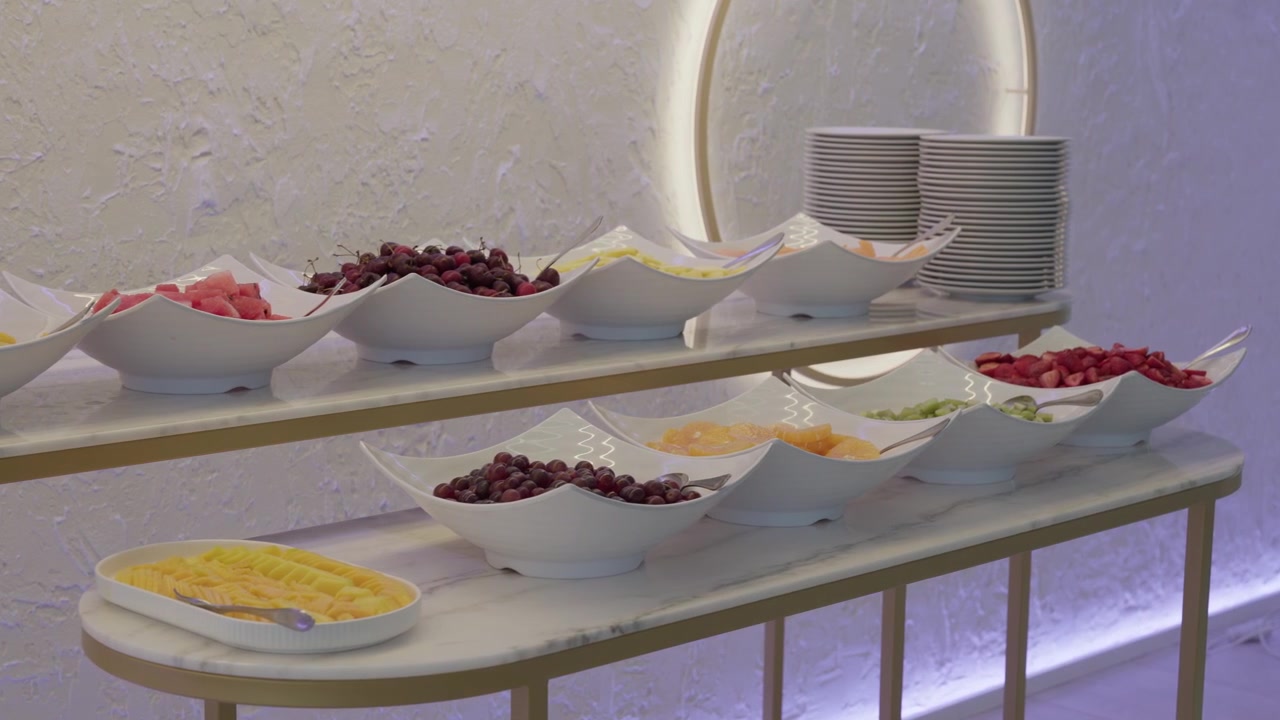 Cuencos blancos de cerezas, sandía, fresas y melón sobre un mostrador de bufé de mármol.