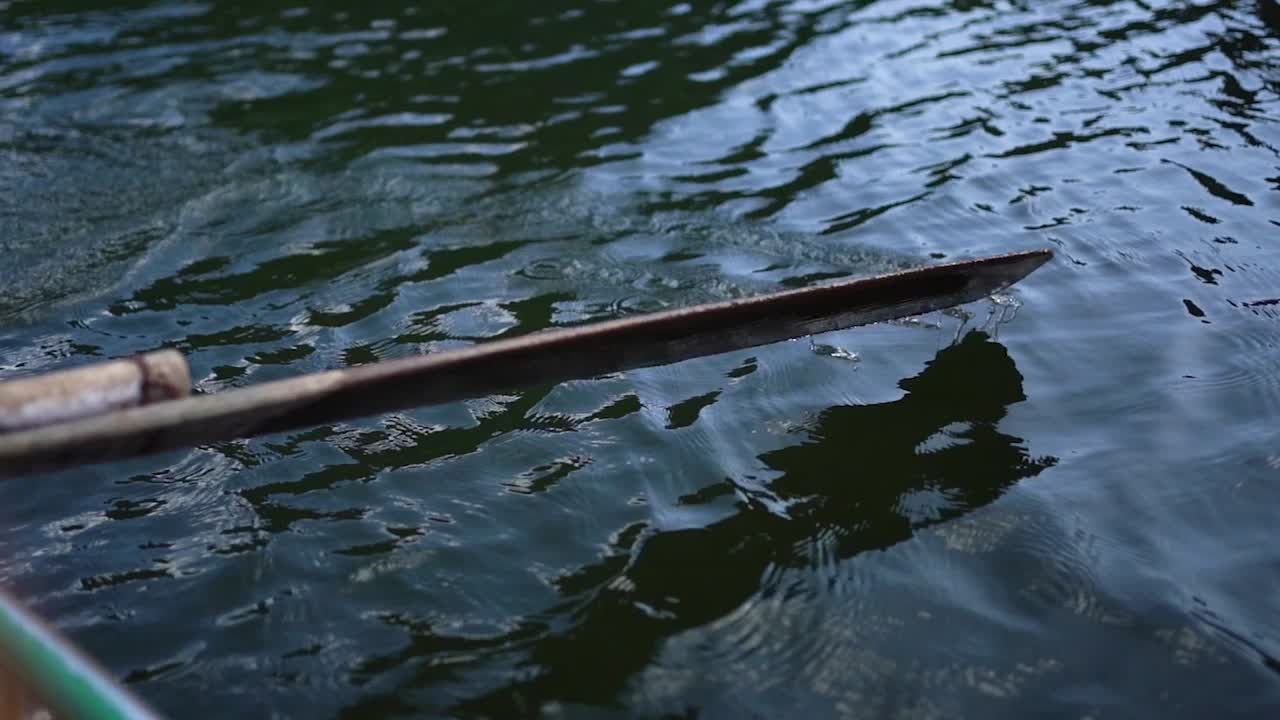 Close-up shot of wooden Oar in the river paddling in Slow motion