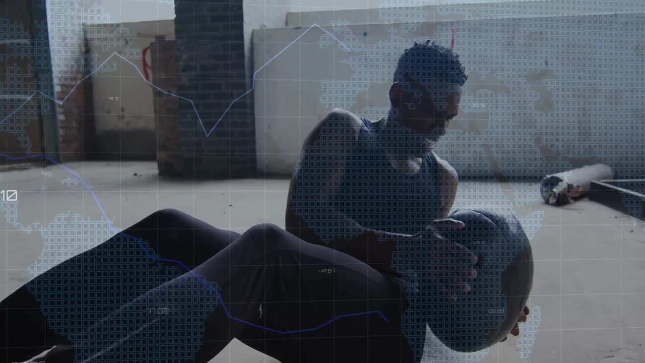 Man grabbing medicine ball on floor, twisting core as data overlays rising for fitness tracking