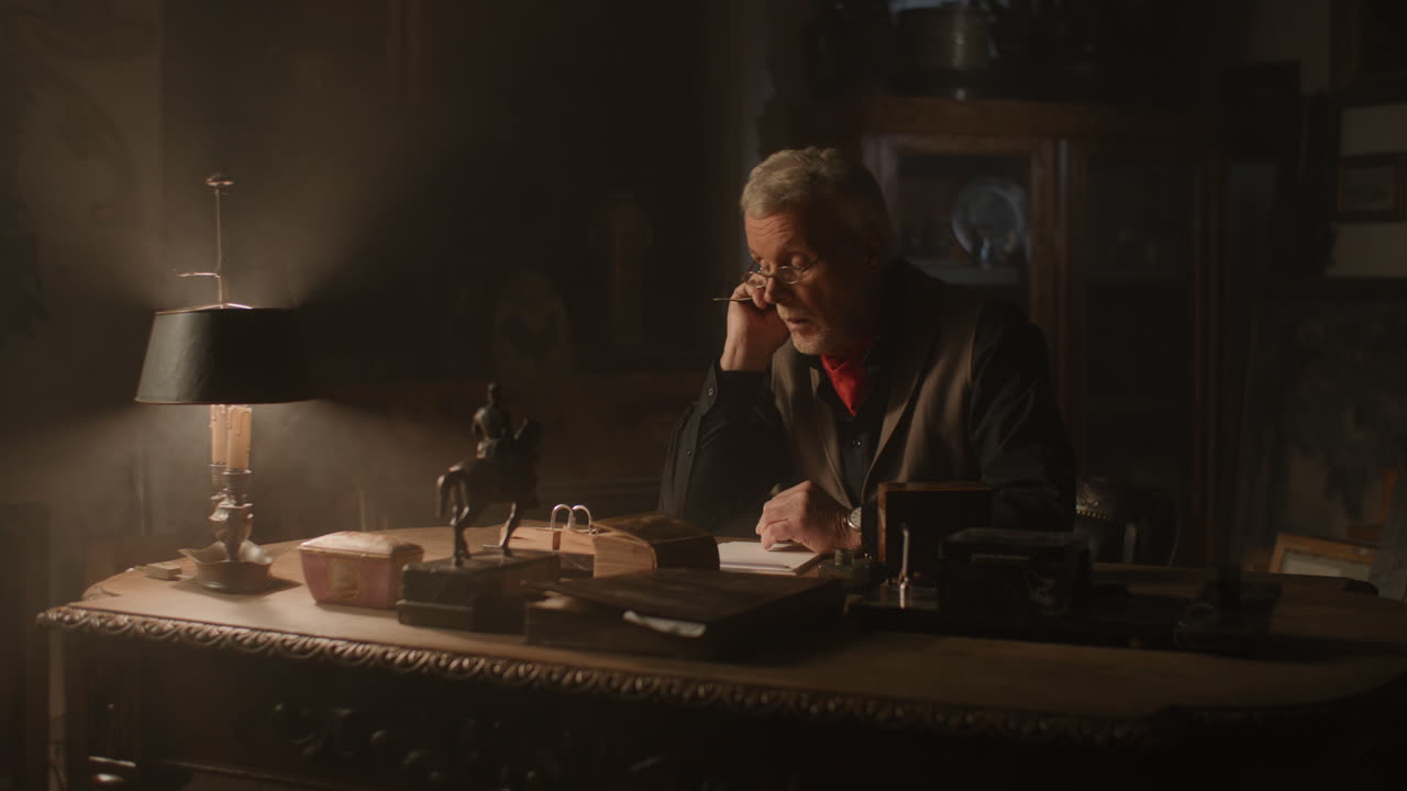 Older passionate man evaluates an old watch in his office at night