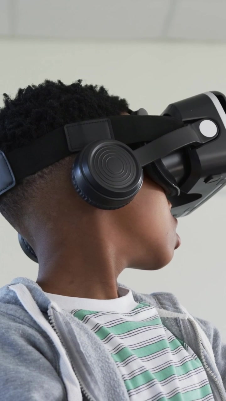 Vertikal video: Reagerende teenager i grå hættetrøje med VR-headset og ørekopper, drejer hovedet, når demo starter i laboratorium.