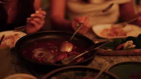 warm, intimate dinner setting with friends enjoying a hot pot meal. dim lighting creates a cozy atmosphere