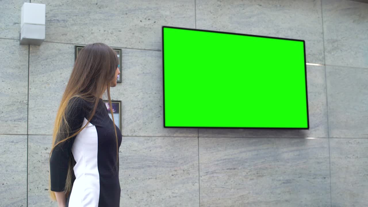 젊은 미소 짓는 사업가 여성이 큰 녹색 스크린에서 프레젠테이션을 하고 있습니다.