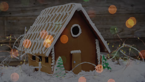 animation of spots of light over gingerbread house in snow