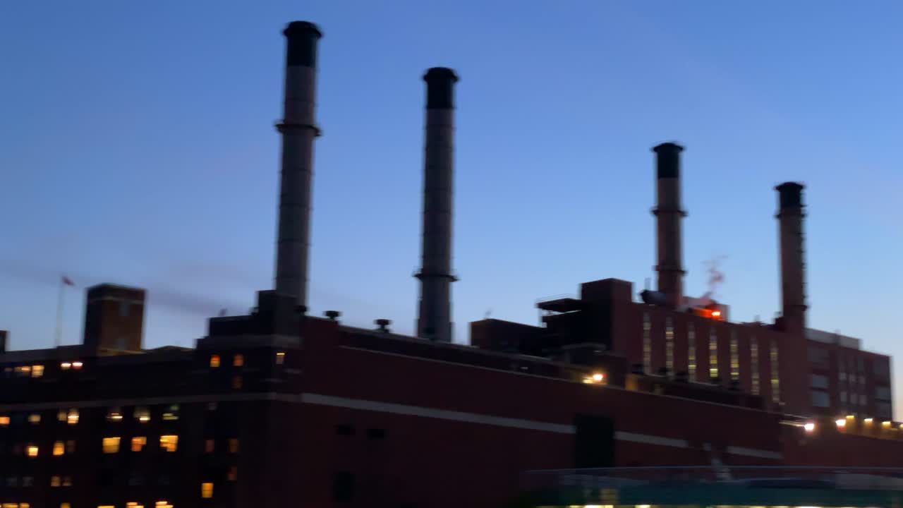 Industribygning med rørledninger og damp ved en blå solnedgang fra en båd i New York