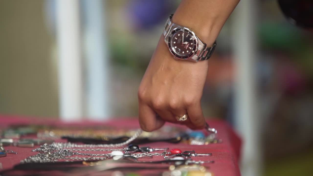 primer plano de la mano femenina eligiendo joyas del mercado de pulgas de la calle mano con reloj y anillo de plata, algunas pulseras en la mesa
