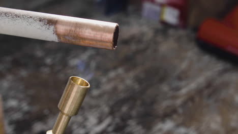 a reclaimed copper pipe is being heated with a blow torch