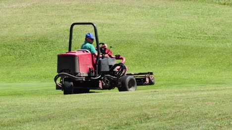 a person operates a riding mower, trimming a vibrant green lawn on a sunny day.