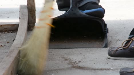 Using-broom-to-sweep-into-black-dustpan