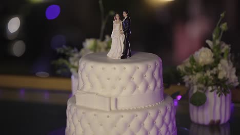 Elegant-wedding-cake-with-couple-topper-and-bokeh-background