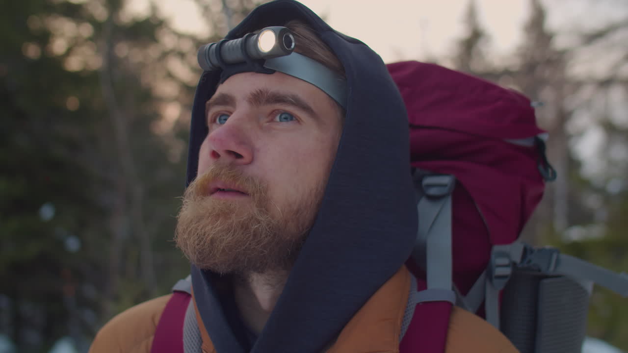 Bearded Tourist with Headlamp Looking around in Winter Forest