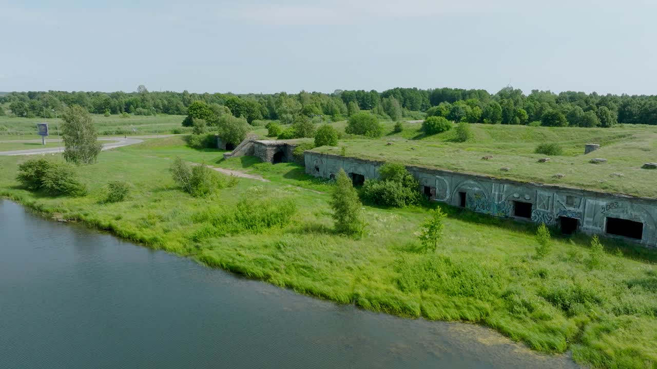 аэрофотосъемка заброшенных исторических бетонных приморских укреплений, южных фортов возле пляжа балтийского моря в лиепае, солнечный летний день, широкий снимок дрона, движущегося назад