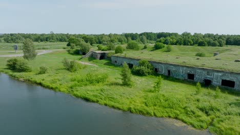 Blick-Aus-Der-Luft-Auf-Verlassene-Historische-Betonbefestigungsgebäude-Am-Meer,-Südliche-Festungen-In-Der-Nähe-Des-Ostseestrandes-In-Liepaja,-Sonniger-Sommertag,-Weiträumiger-Drohnenschuss,-Der-Sich-Rückwärts-Bewegt