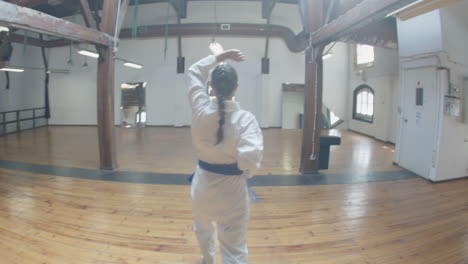 chica enfocada demostrando movimientos de karate en la sala de práctica