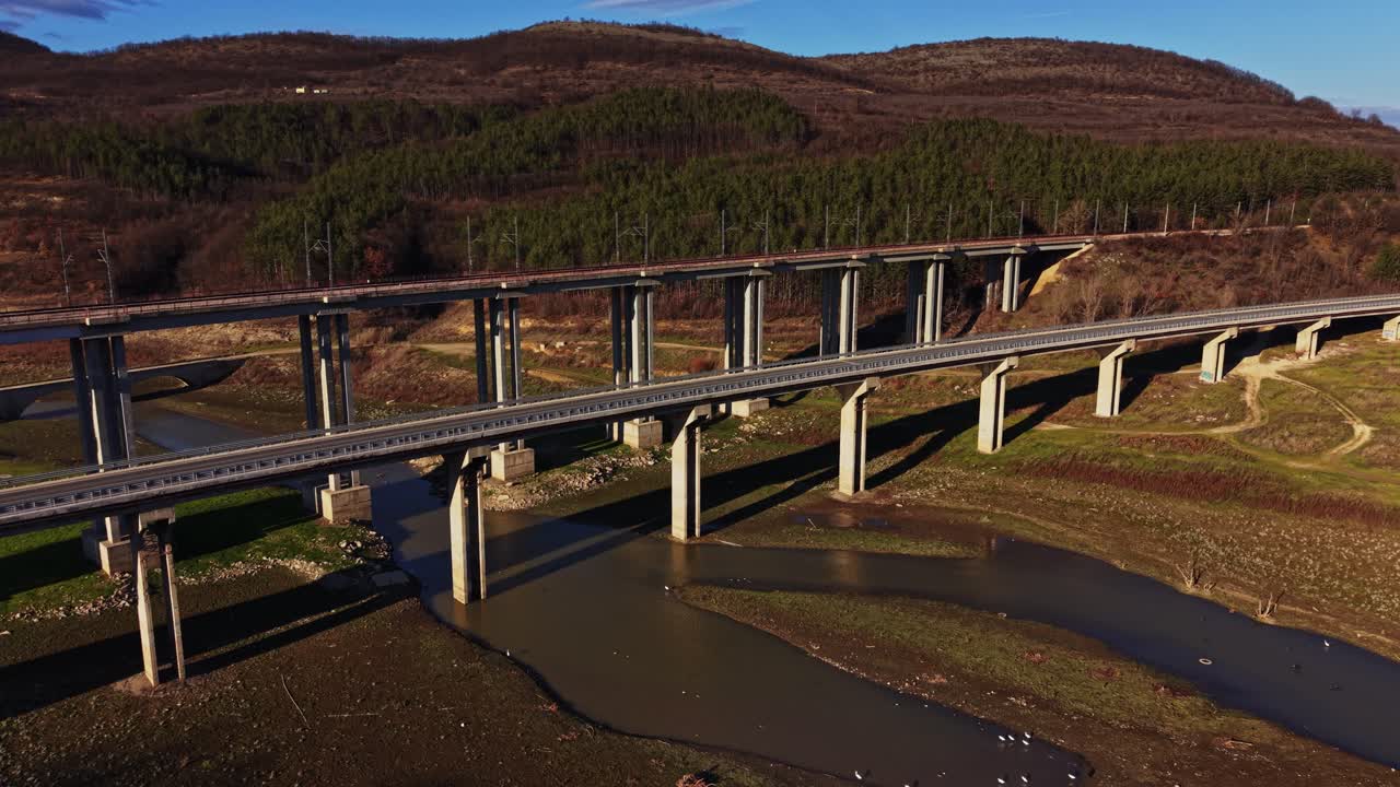Ponte che attraversa il fiume sotto un cielo blu vicino a una foresta in zona rurale