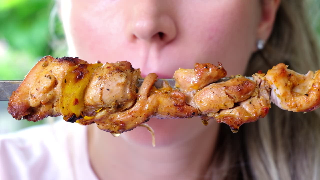 Close up of a woman eating meat from a skewer at a restaurant