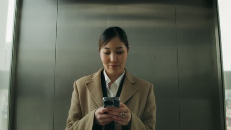 woman using phone in an elevator