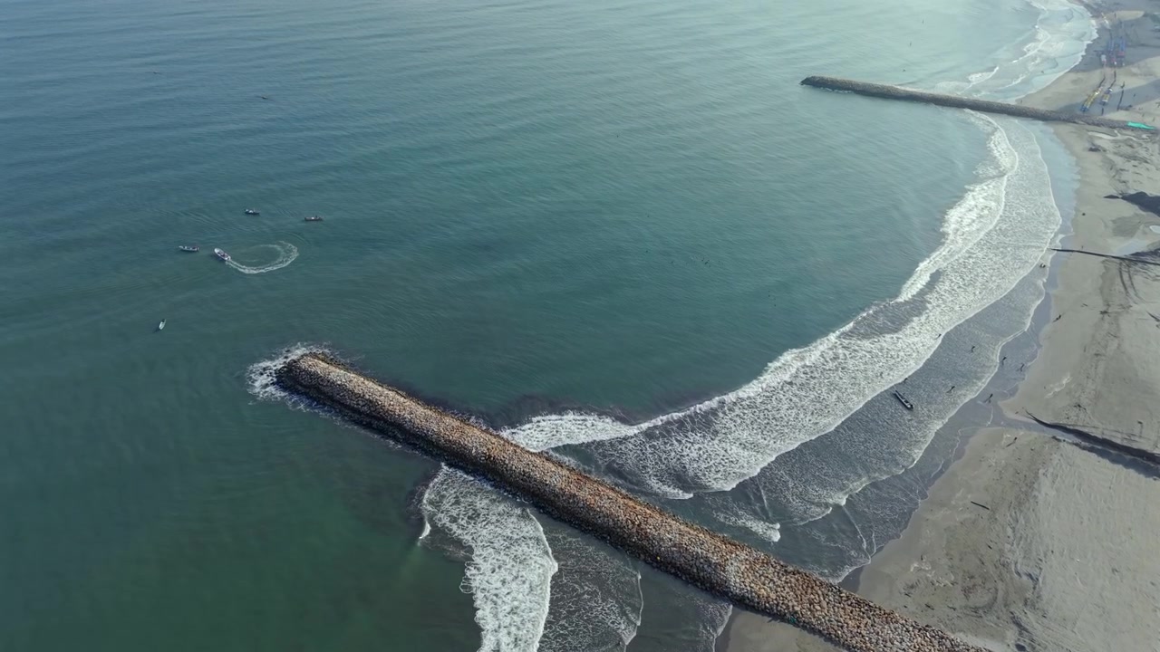 Impresionantes imágenes aéreas de dron capturan la playa de Bocagrande en Cartagena, Colombia, con distintivos rompeolas de piedra, suaves olas oceánicas, aguas tranquilas y una amplia costa arenosa