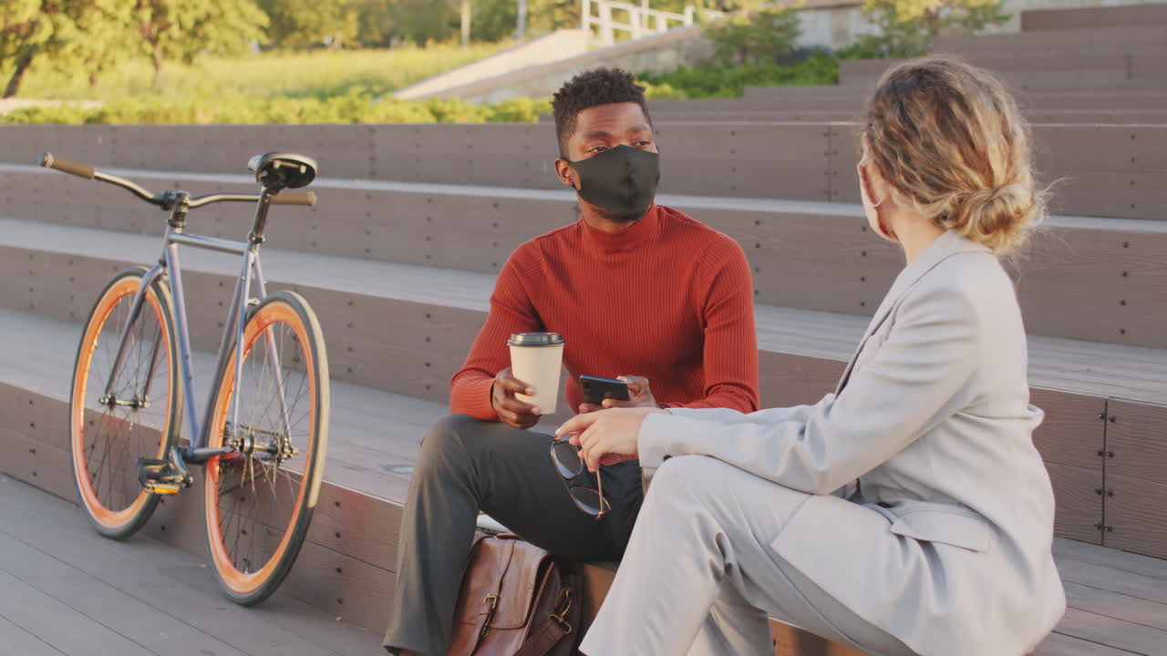 Interracial Business Couple in Face Masks Chatting Outdoors