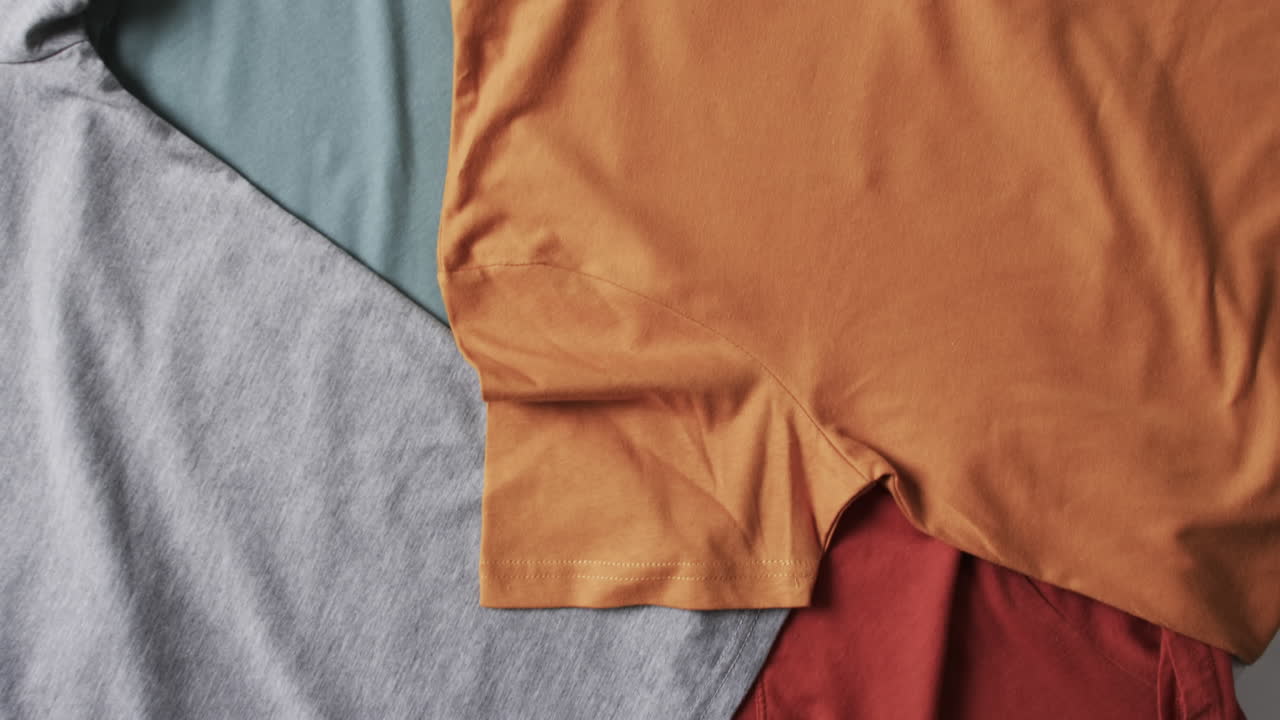 ⁇ 색 배경에 복사 공간이 있는 다채로운 티셔츠의 평평한 레이의 비디오