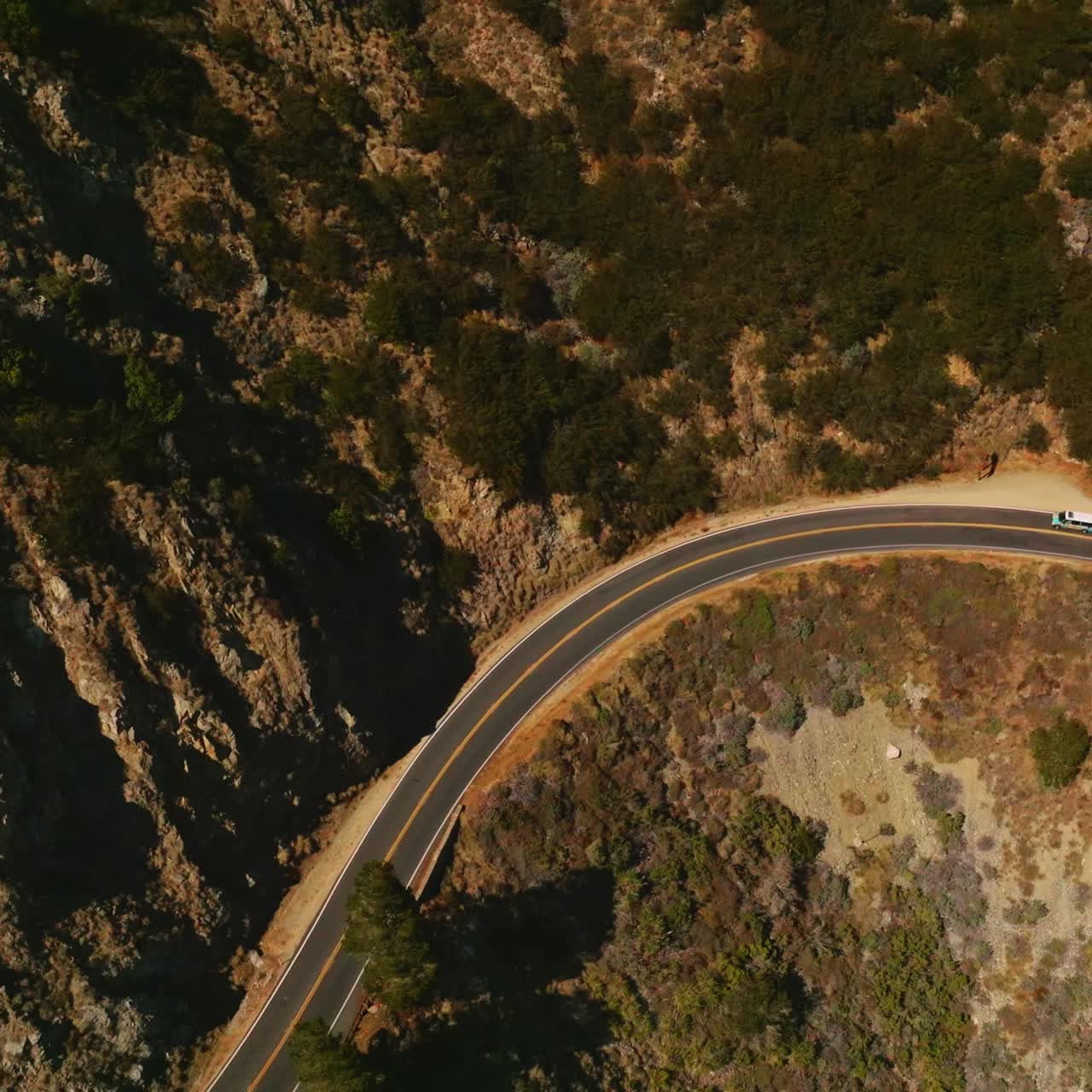 Motorway passing through the huge mountain. Cars moving by the dangerous road at the edge of rock. Aerial view