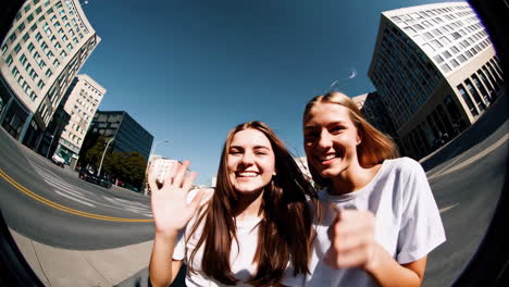happy young women waving and smiling in a fisheye city view