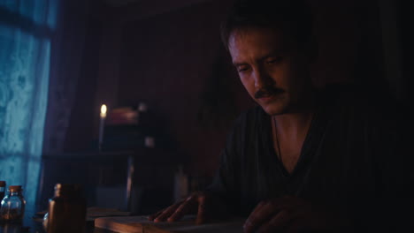 man with moustache reading an old book by candlelight