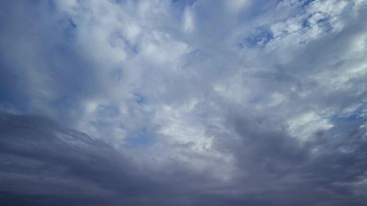 Time-lapse of light white clouds across a bright blue sky, turning into dramatic thunderclouds.