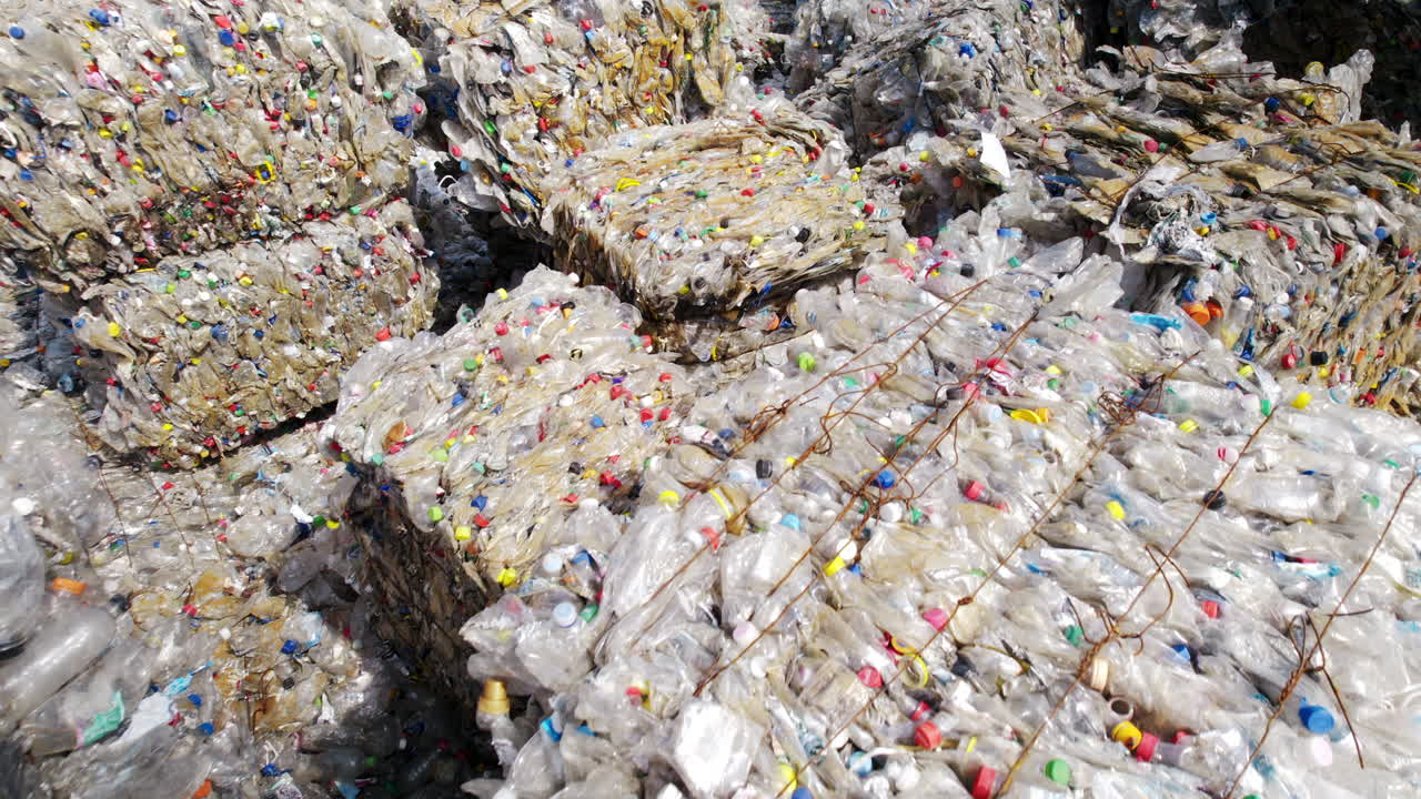 Multiple cubes of compressed transparent plastic garbage at waste recycling factory in open air