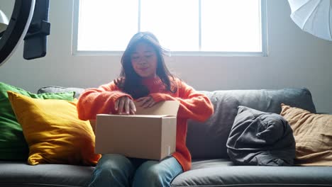 woman unboxing package on sofa