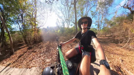 camera pointing at happy man riding motorcycle on country road on sunny day. real time